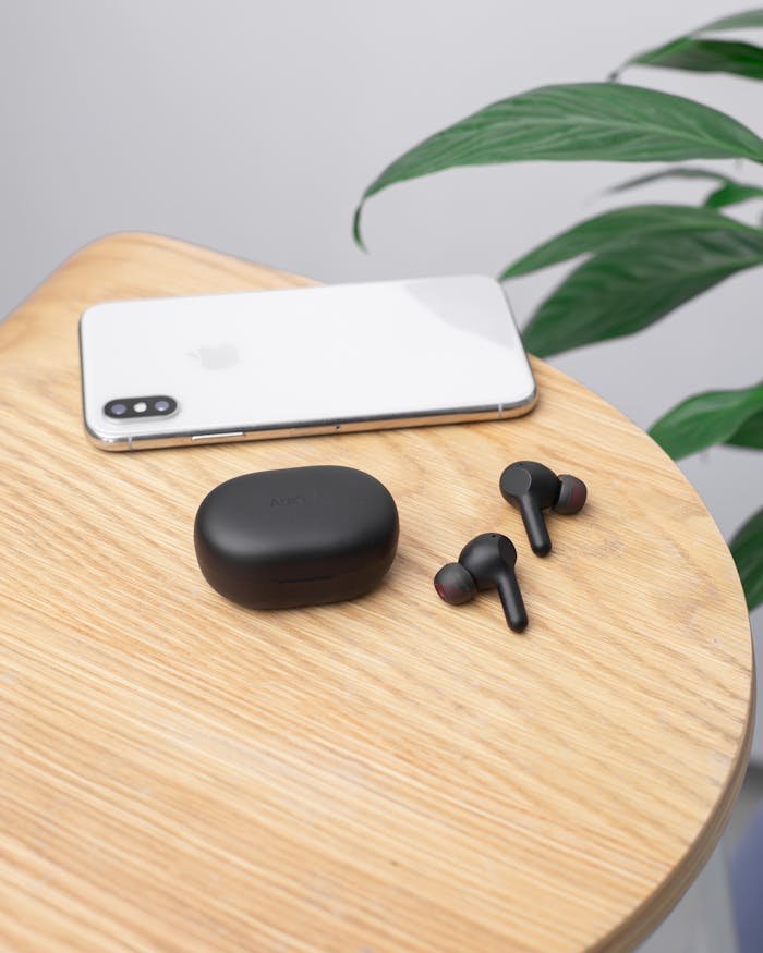 Wireless earphones and smartphone on a wooden table indoors. Ideal tech and lifestyle photo.