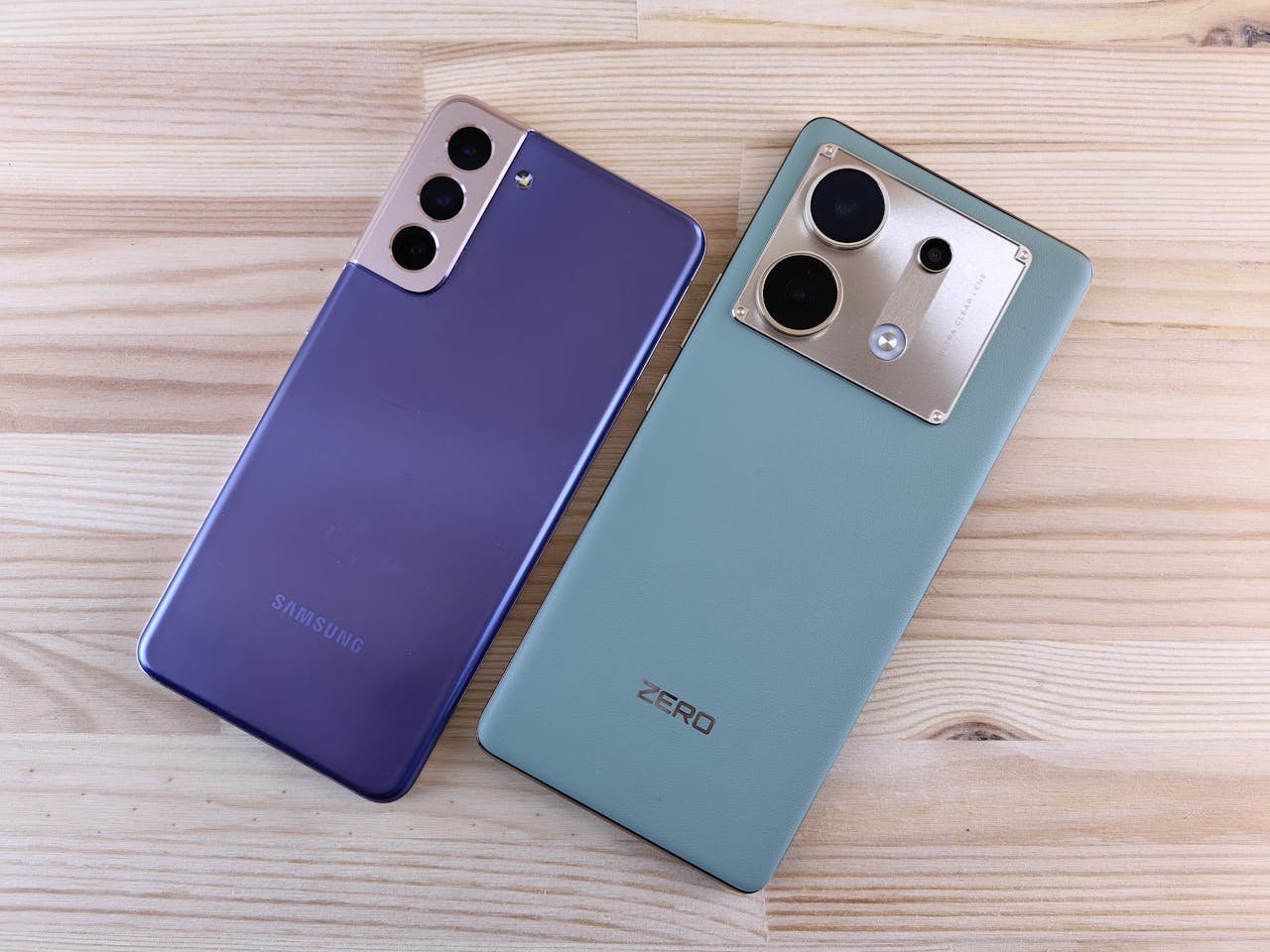 Two smartphones on a wooden surface, showcasing sleek design and modern technology.